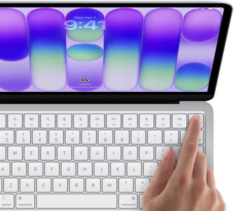 MacBook Neo, silver colour, showing login screen, person's finger on Touch ID sensor in top-right corner of keyboard